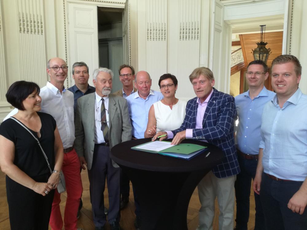 Jan Romel van de gelijknamige bouwfirma ondertekent met plezier de verkoopsovereenkomst van het kasteel Blauwhuis, onder het goedkeurend oog van een delegatie van het stadsbestuur en de vzw Gillès de Pélichy. © PVH