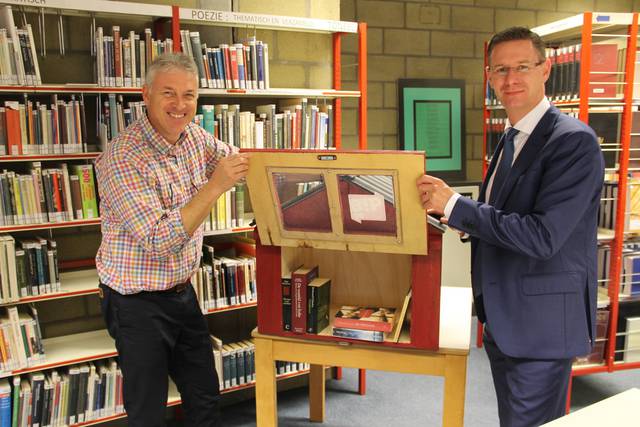 Bibliothecaris Nicolas Cappelle en bibschepen Kurt Himpe (N-VA) vullen het eerste boekenruilkastje. - Foto VDI
