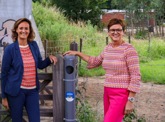 Schepen Lisbet Bogaert en Caroline Maertens bij de hondenpoepbuis