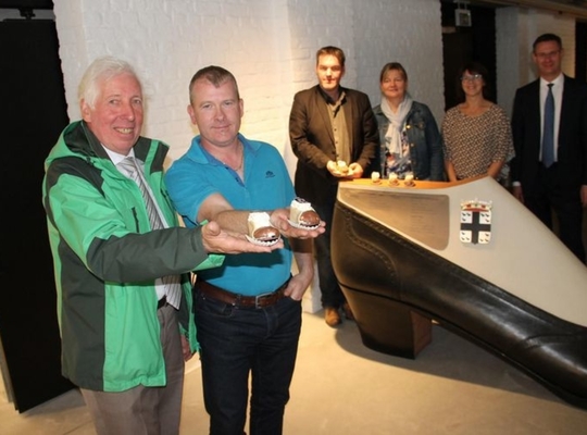 © VDI Bakker Jean-Pierre Verfaillie (links) gaf toestemming aan collega Kris Tanghe om het Izegems Schoentje opnieuw te maken. Dat gebeurde op voorzet van Danny Wittebroodt (eerste van links achteraan). Op de foto zien we nog bakkersvrouw Daisy Depoortere